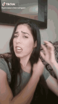 a woman with long black hair is making a funny face with a tiktok watermark