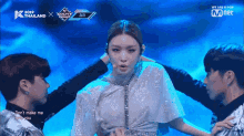 a woman stands on a stage surrounded by men with the words " we are k pop " on the bottom