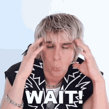 a young man is making a funny face while holding his head with the word wait written on it
