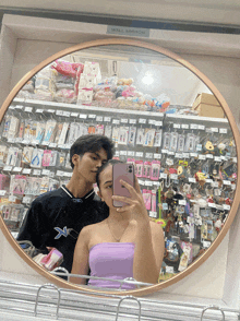 a woman taking a picture of herself and a man in front of a wall mirror