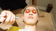 a man wearing sunglasses is getting a treatment on his face .