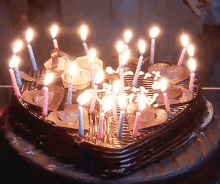 a heart shaped birthday cake with lots of lit candles on it