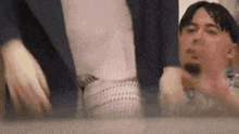 a man is making a funny face in front of a mirror while another man looks on .