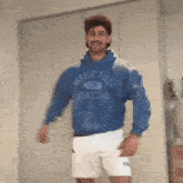 a man wearing a blue forest hills athletics hoodie and white shorts is dancing in a room .