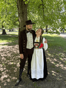 a man and a woman standing under a tree