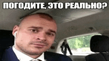 a man in a suit and tie is sitting in the driver 's seat of a car .