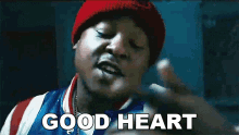 a man wearing a red beanie and a blue and white jacket is saying good heart