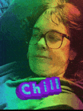 a woman wearing glasses is laying down with a chill sticker on her chest