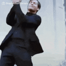 a man in a suit is dancing in front of a stop motion factory watermark