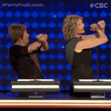 two women are standing next to each other with their arms raised in the air in front of microphones ..