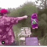 a man in a floral shirt is pointing a gun at a stuffed animal