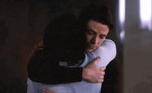 a man and a woman are hugging each other in a room .
