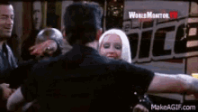 a group of people are hugging in front of a sign that says world monitor .