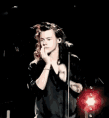a young man is singing into a microphone on a stage .