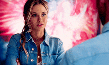 a woman in a denim jacket is talking to a man .