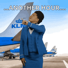 a klm flight attendant is pointing at the tail of a plane