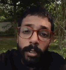 a man with a beard and glasses is making a face .