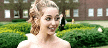 a woman in a dress is smiling and looking at the camera .