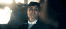 a man in a suit is being shot in the head with a revolver .