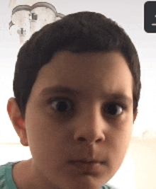 a close up of a young boy 's face with a cloud on the wall behind him