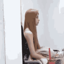 a woman with long red hair is sitting in a chair .