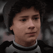 a young boy with curly hair is wearing a gray hat