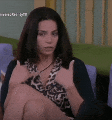 a woman is sitting on a couch with her hands folded in front of a tv screen that says niversoreality tv