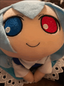 a stuffed animal with blue hair and red eyes is smiling