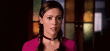 a woman wearing a choker and braids is standing in front of a door .