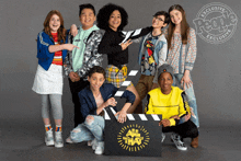 a group of young people posing for a photo with a sign that says ' all the way ' on it