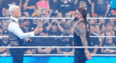 a couple of men are standing in a wrestling ring talking to each other .