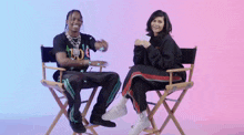 a man and a woman are sitting in directors chairs and smiling