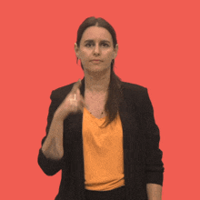 a woman wearing a black jacket and an orange shirt is making a funny face