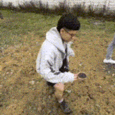 a man in a white hoodie is kneeling down in a field