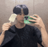 a man is taking a picture of himself while holding a popsicle in front of a mirror