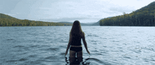 a woman in a black bikini is standing in the water