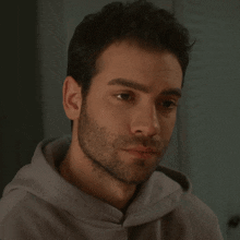 a man with a beard is wearing a gray hoodie