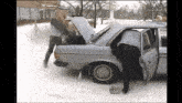 a man is getting out of a car with the trunk open in the snow