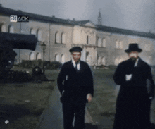 two men are walking in front of a building with a 24 ack sticker on it