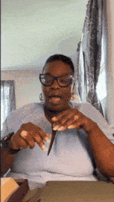 a woman wearing glasses is sitting at a table with her tongue out