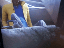 a man in a yellow jacket is sitting on a bed