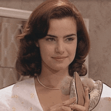 a woman wearing a pearl necklace is holding a pair of heels