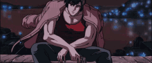 a man in a red tank top is sitting on a ledge with his arms crossed