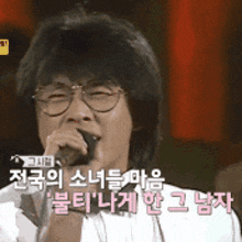 a man with glasses is singing into a microphone