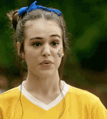 a girl with a blue bow in her hair has a tattoo on her face