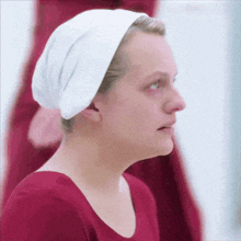 a woman wearing a red shirt and a white headband looks to the side