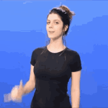 a woman in a black shirt is standing in front of a blue background .