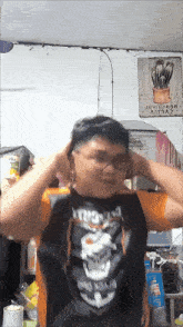 a man wearing a black shirt with a skull on it adjusts his ear buds