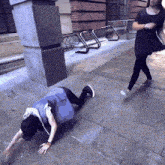 a person is crawling on the sidewalk while another person walks by