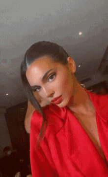 a woman in a red robe is taking a selfie with her hand in her hair .